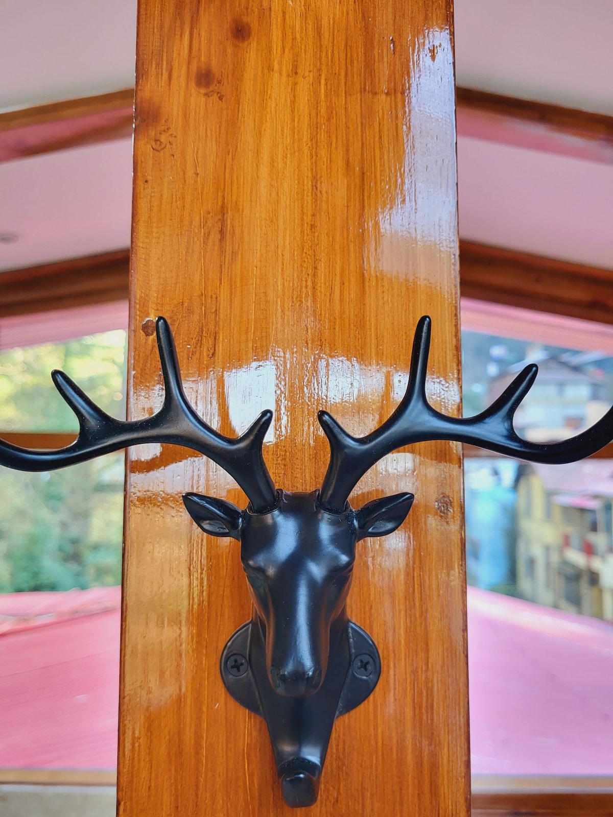 A mounted black deer head with prominent antlers is affixed to a polished wooden column, reflecting the refined decor of the attic suite. Soft colors in the background create a serene atmosphere, providing a touch of artistic flair to the space.