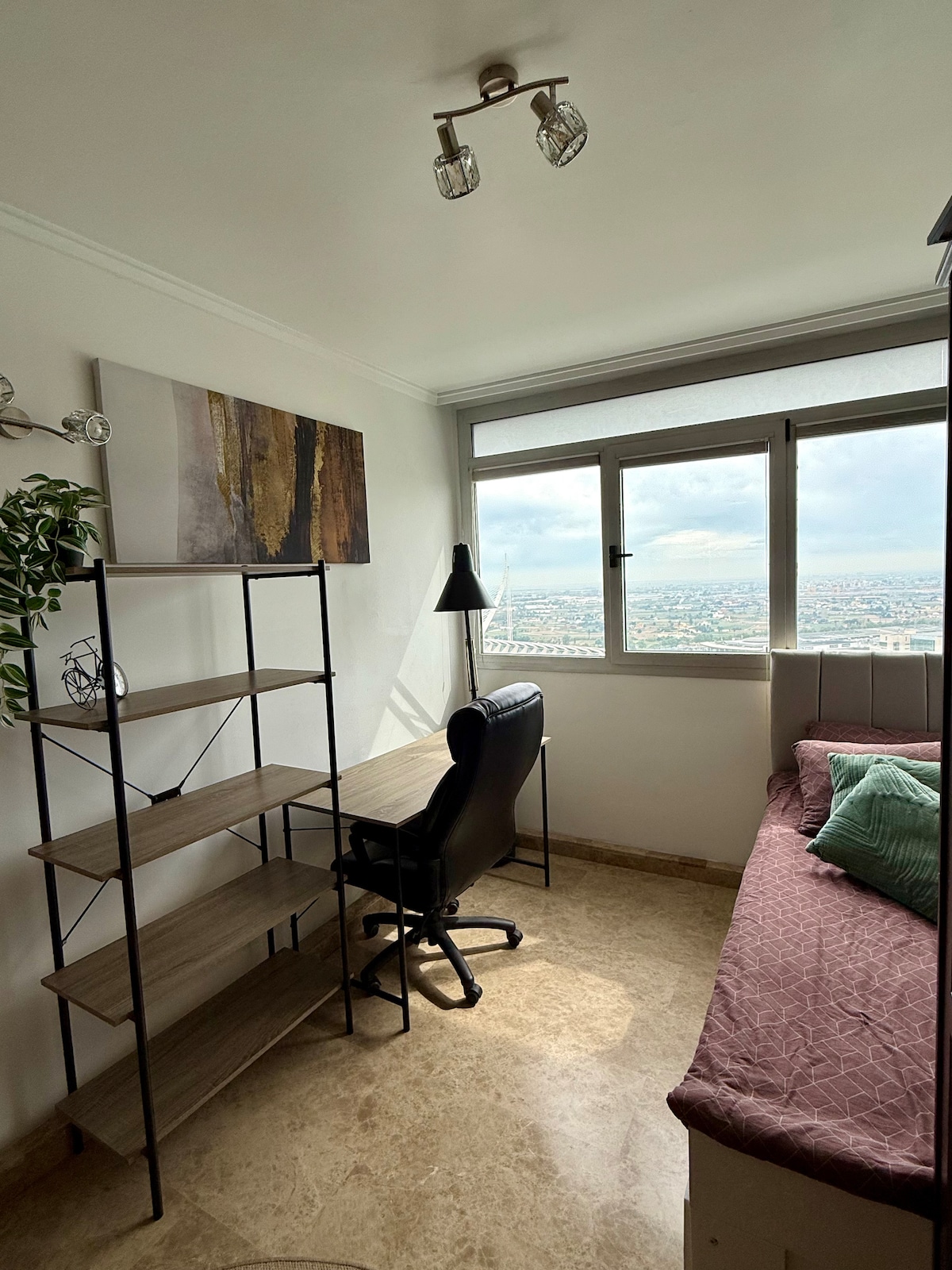 Habitación luminosa con una cama individual que se extiende a una cama doble y cómoda para dos personas. Incluye un escritorio, estantes y grandes ventanales con increíbles vistas de la Ciudad de las Artes y las Ciencias.