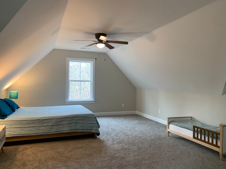 Ova spavaća soba na katu ima madrac od memorijske pjene Queen.   Primijetite dječji krevet s desne strane.