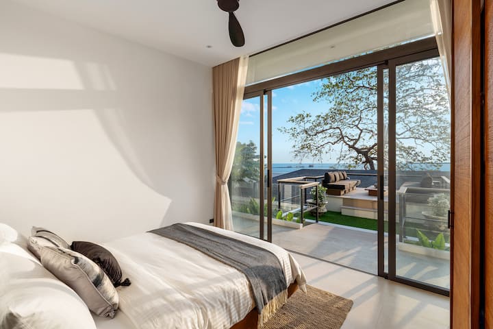 モダンなリラクゼーション–クイーンベッドの贅沢さと海のパノラマで快適に過ごせます。