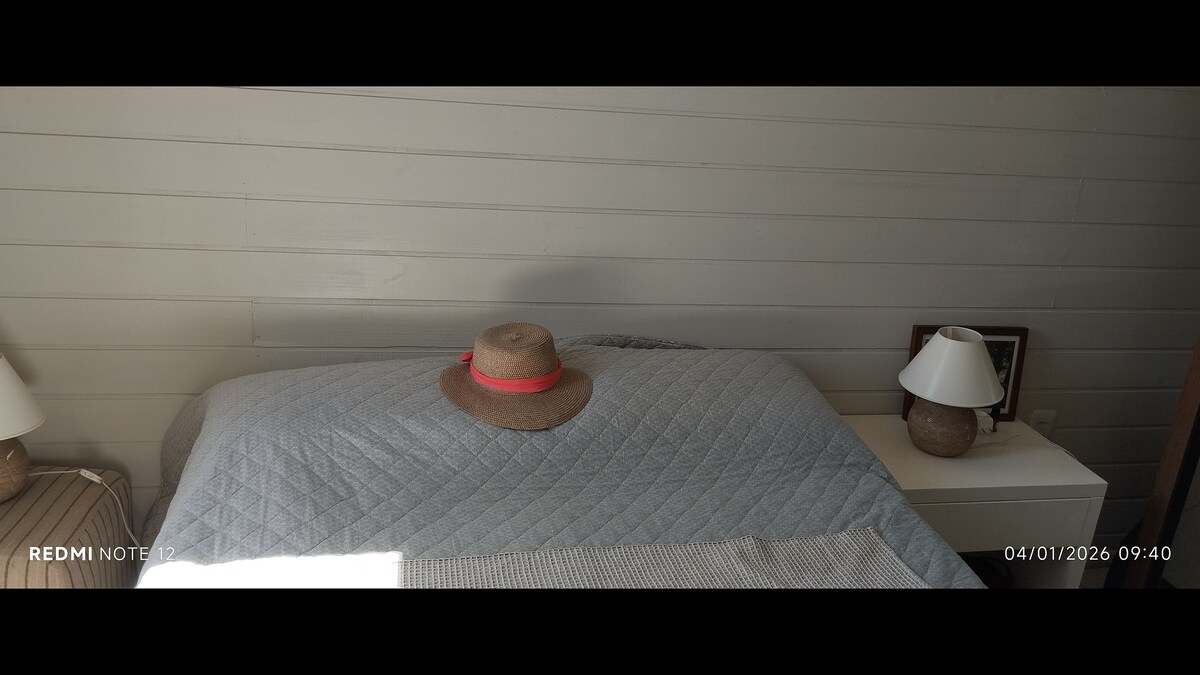 Krevat dopio me një tavolinë pranë krevatit dhe një puf me abazhurë.
