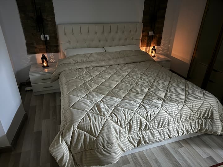 נופש ליוקרה בחדר השינה הראשי המרווח שלנו, עם מיטת קינג סייז מפוארת והלבשה אלגנטית לאור זכוכית