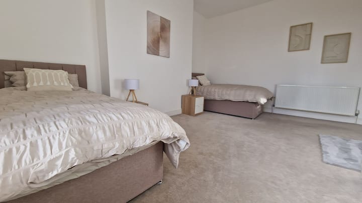 חדר שינה בקומה הראשונה, מיטה זוגית ומיטת יחיד עם טלוויזיה נטפליקס, מלתחה