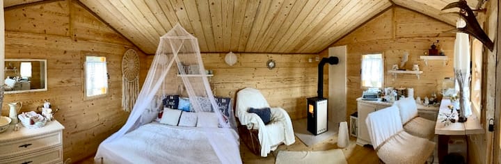 Interiér domčeka – posteľ s baldachýnom, kreslo a piecka na drevo