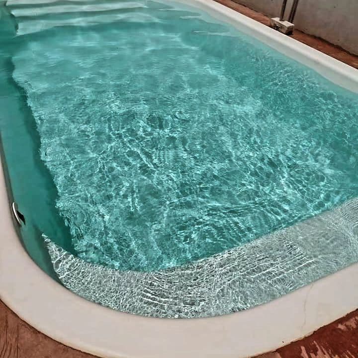 A clear swimming pool is presented, featuring calm, shimmering water. The pool's smooth edges are complemented by a light-colored deck, creating a serene environment suitable for relaxation.