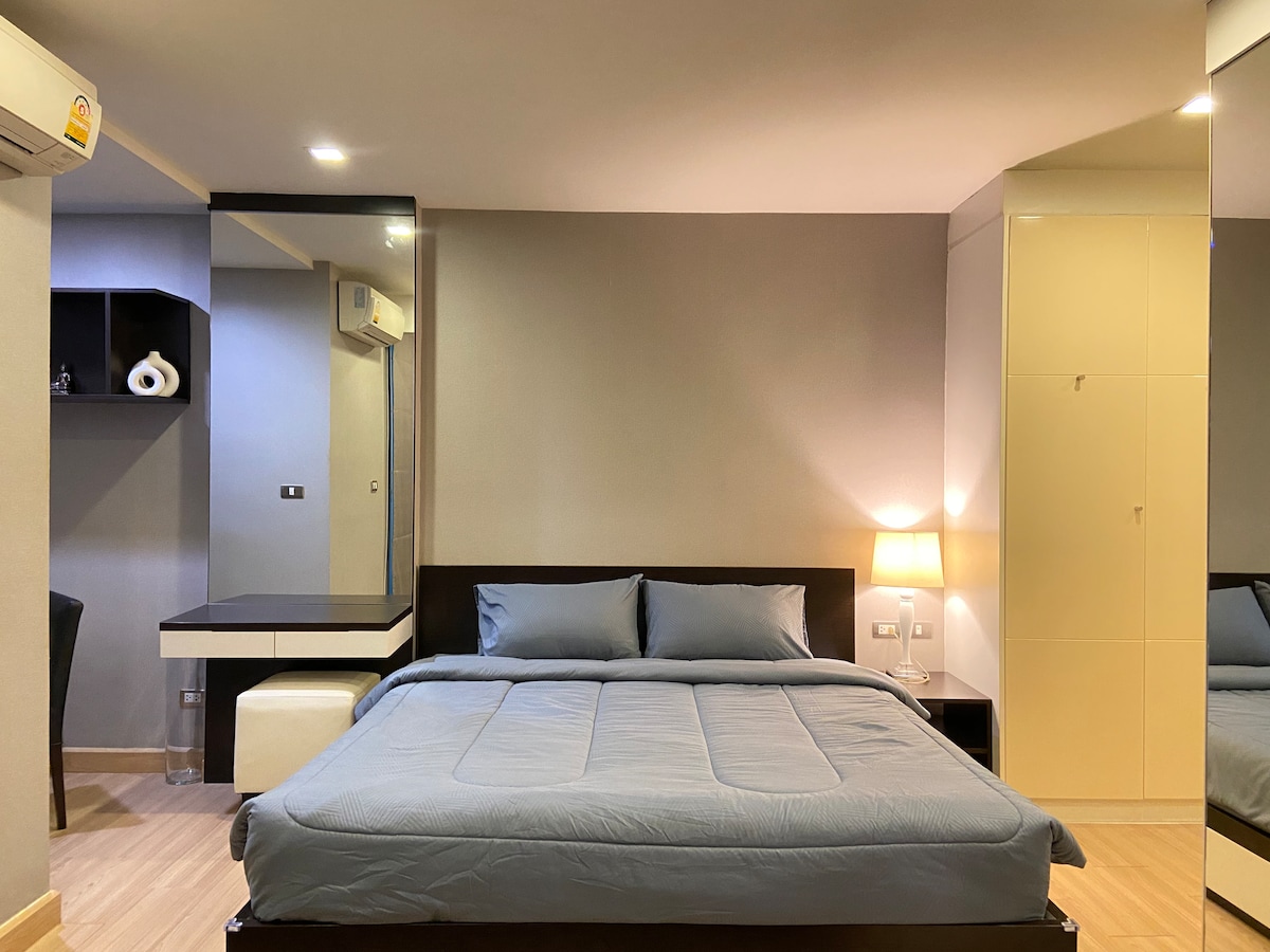 宽敞的卧室区，配有纳米羽绒枕头的6英寸床、带床头灯的床头桌、化妆梳妆台和衣柜