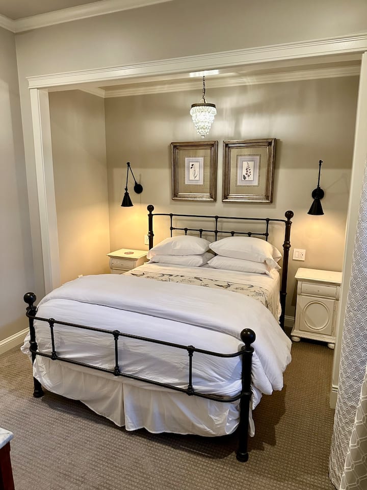 A curated blend of period antique and modern furnishings and appointments make for a special and inviting space to rest and relax.  This room features a unique nook wrapping the bed and a little glam with a vintage-feel mini chandelier.