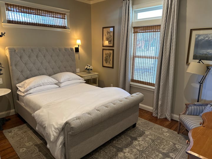 A transom window adds a wonderful natural light to this well-appointed and spacious bedroom.  As with all bedrooms in the house, this room features convenient bedside USB B-C wall plugs and reading lights from wall sconces, as well as luxury linens.
