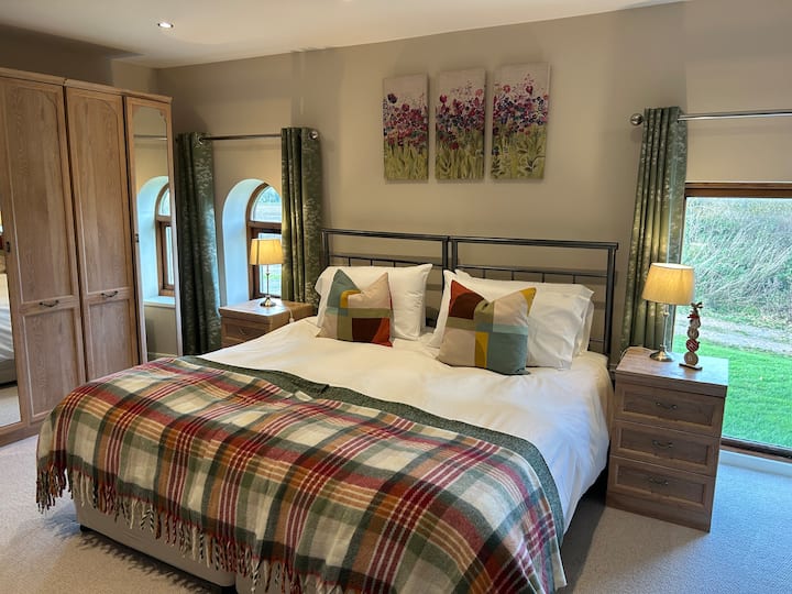 Krevat me përmasa super mbretërore në dhomën kryesore të gjumit