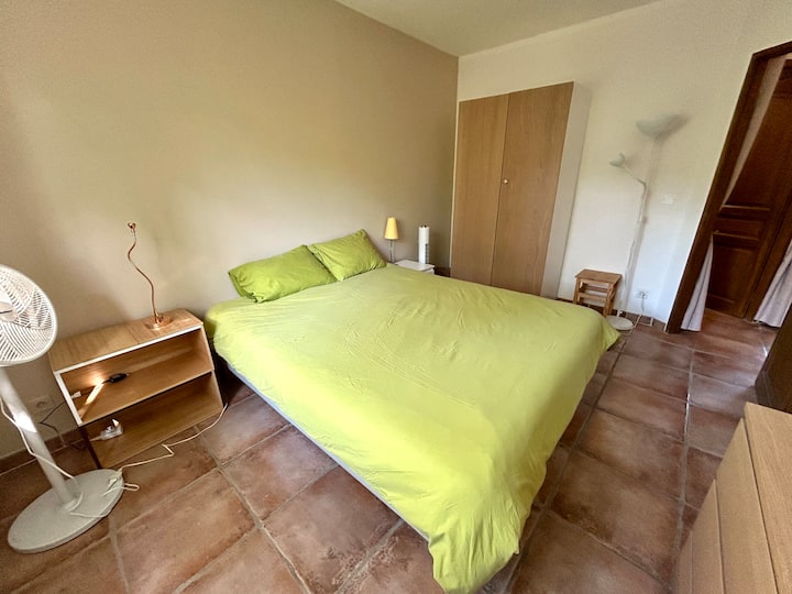 Spavaća soba s bračnim krevetom dimenzija 160 × 200 iz koje se pruža pogled na vrt.
Namještaj za odlaganje (komoda, ormar s vješalicama), mreža za prozor, drvene rolete, prijenosni ventilatori, produžni kabeli.