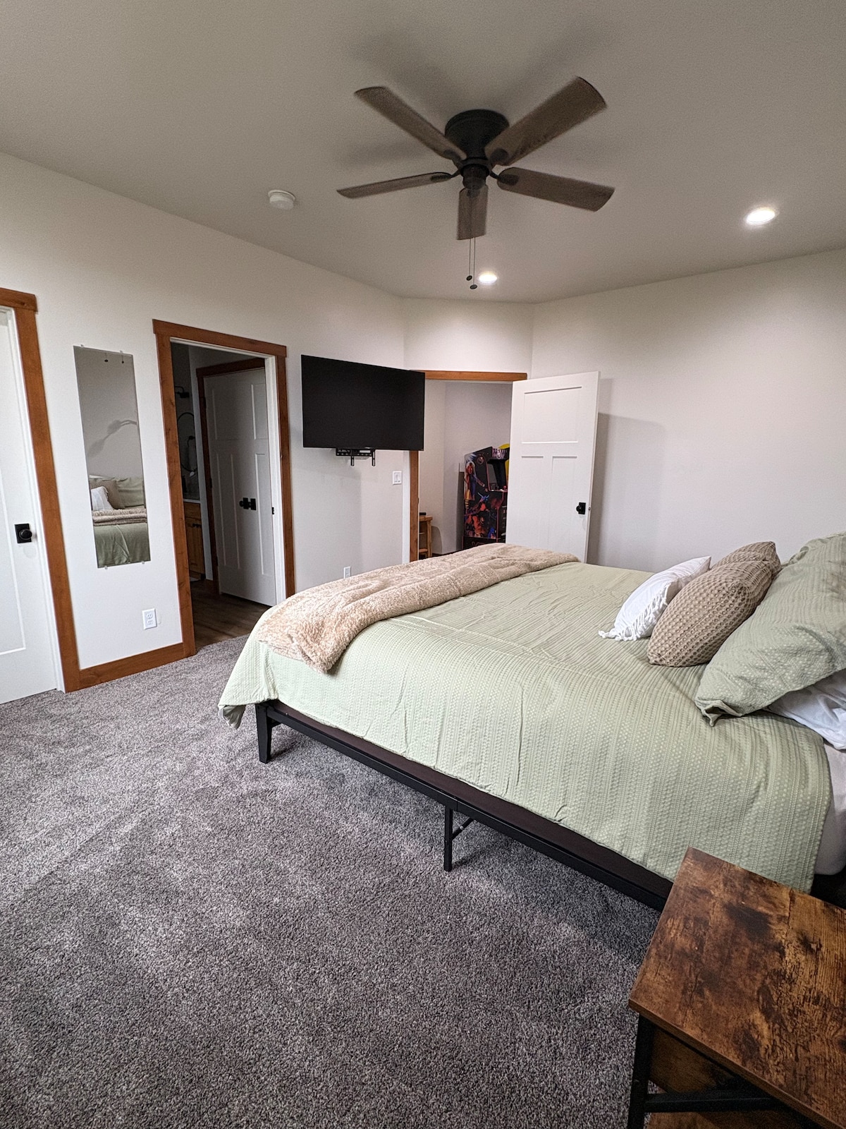 A large king suite with fresh bedding, pillows, and a soft throw. Includes a wall-mounted TV, nightstands, and ample space. And has a private ensuite bathroom features a double-sink vanity, and towels for added convenience and privacy. 