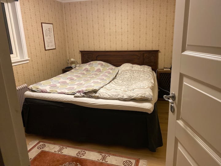 เตียงคู่ที่มีด้านที่นุ่มและแน่นกว่า โต๊ะข้างเตียงพร้อมโคมไฟบนเตียงพื้นไม้เนื้อแข็ง