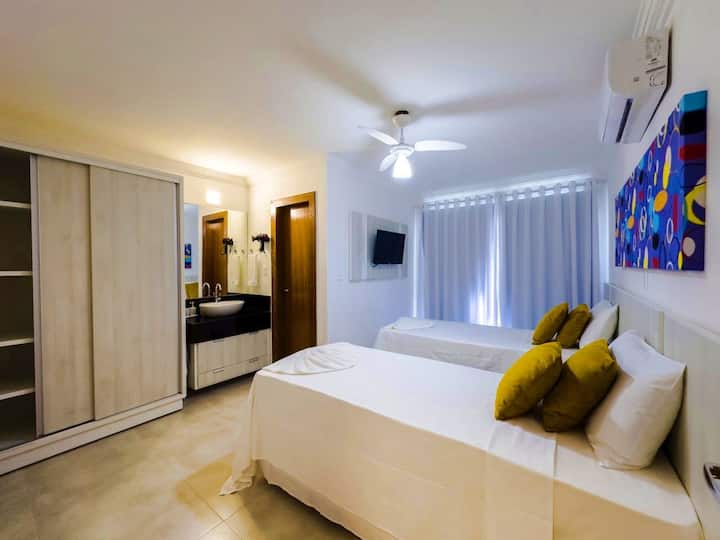 Slaapkamer 2 met eigen badkamer, uitgerust met vier eenpersoonsbedden, airconditioning, smart-tv, verduisteringsgordijnen, beddengoed, ruimte om kleding op te bergen, plafondventilator en hangers.