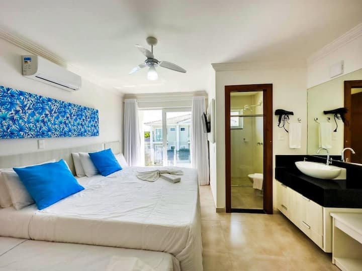 Slaapkamer 1 met eigen badkamer, uitgerust met een queensize bed en twee eenpersoonsbedden, airconditioning, smart-tv, verduisteringsgordijnen, beddengoed, ruimte om kleding op te bergen, werkruimte en directe uitgang naar het zwembad.