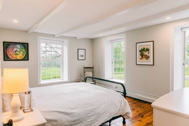 A bright and airy queen bedroom with sunlit windows. Wake up to sweeping views of the farm
