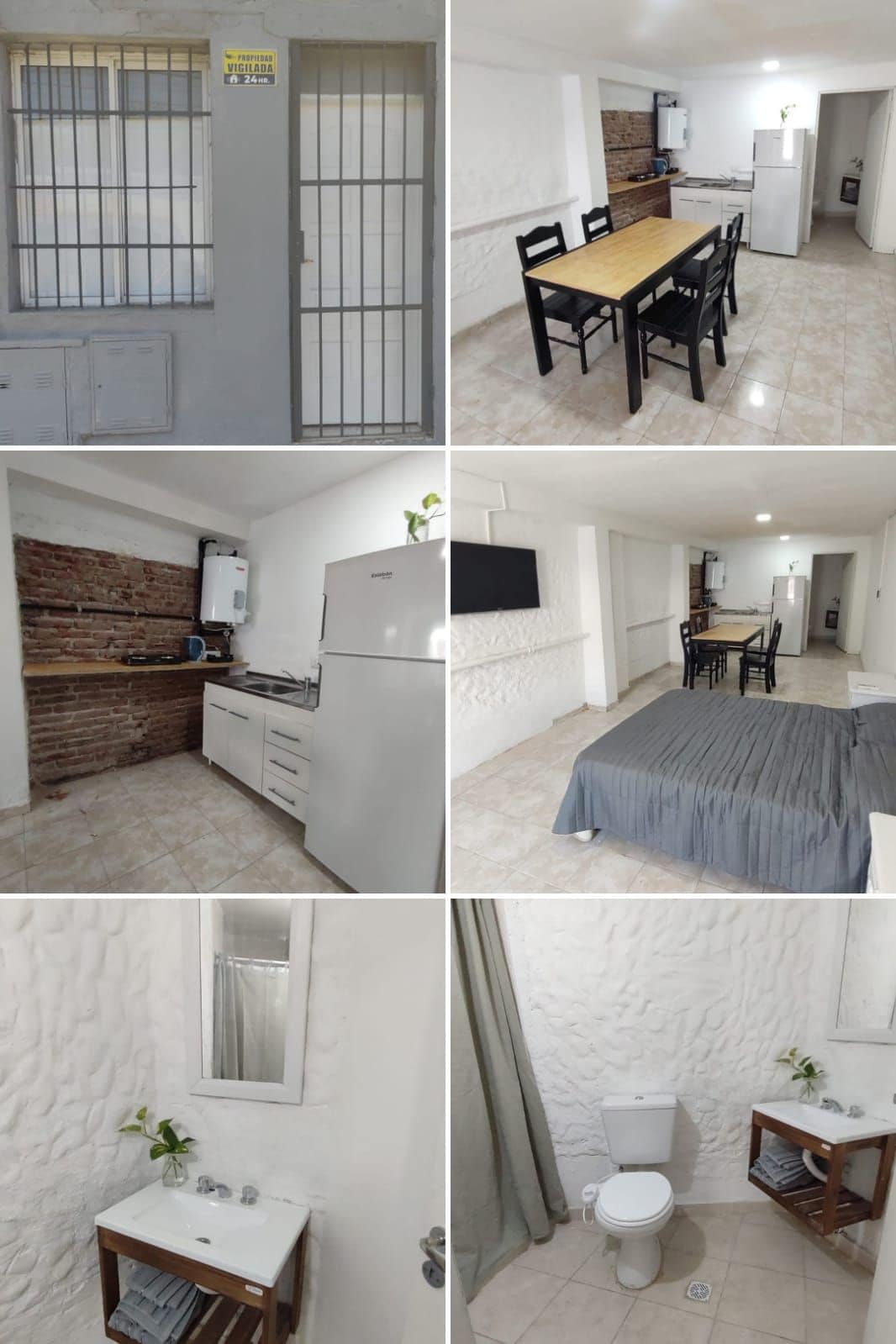 An inviting dining area is furnished with a long wooden table and matching chairs, complemented by a light-flooded space featuring a view of the kitchen. The modern kitchen showcases white cabinets and appliances, while a cozy sleeping area contains a spacious bed with soft grey bedding. A clean bathroom is equipped with a toilet and a small sink unit.