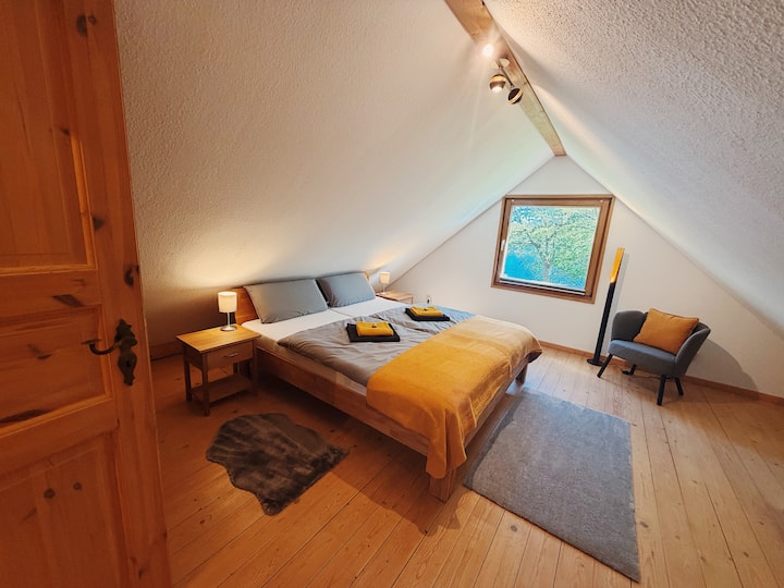 Zur Seeseite ausgerichtetes Schlafzimmer mit Doppelbett (180 × 200cm) aus massiver Eiche. Ausgestattet mit getrennten, OEKO-TEX®-zertifizierten BODYGUARD®-Matratzen und Bettwäsche aus 100% Baumwolle. Fenster mit Moskitonetz und Verdunklungsplissee