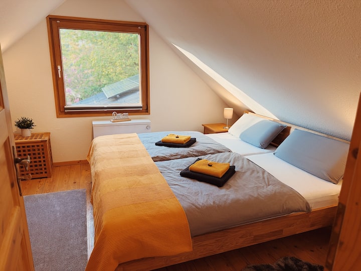 Schlafzimmer zur Landseite mit Doppelbett (180 × 200 cm) aus massiver Eiche. Ausgestattet mit getrennten, OEKO-TEX®-zertifizierten BODYGUARD®-Matratzen und Bettwäsche aus 100 % Baumwolle.