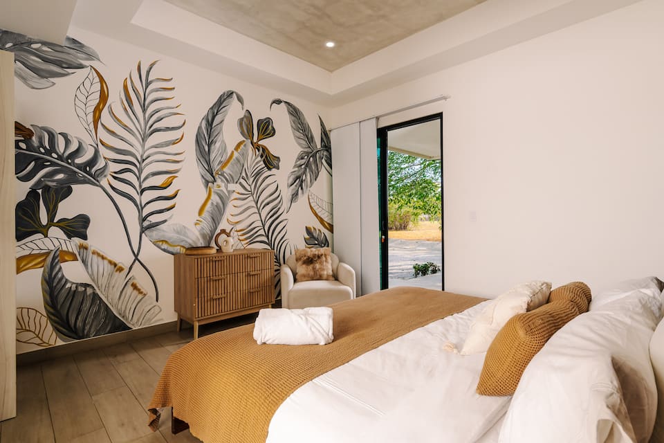 A bedroom with a hand-painted leaf mural