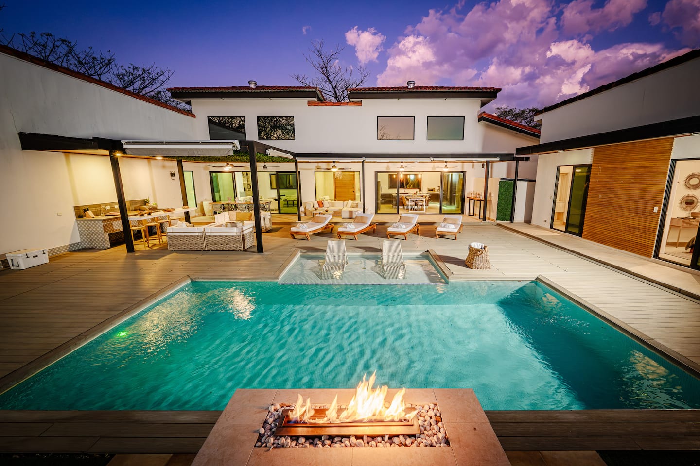 Villa NAUA's pool and house at twilight, a fire bowl lit