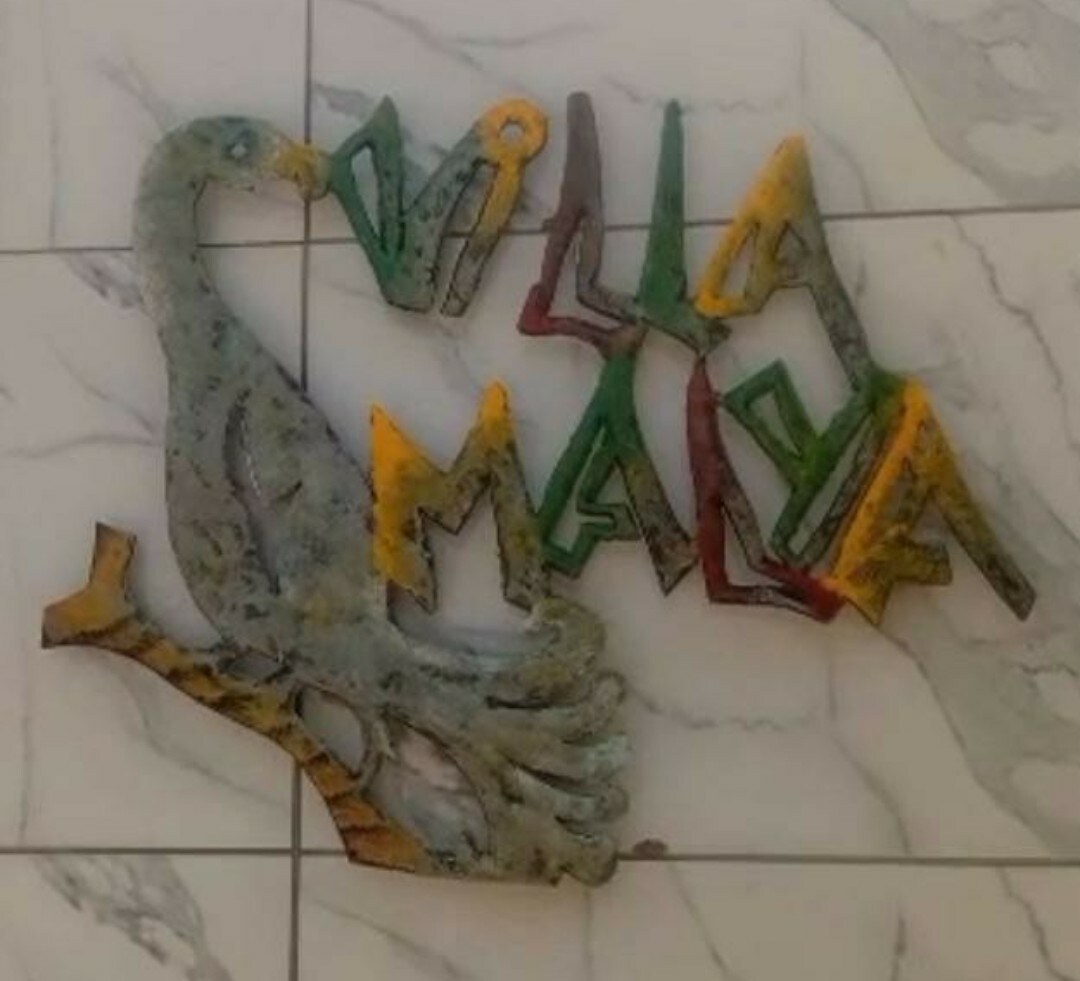 A decorative wall art piece is displayed, featuring a bird perched on a branch. The letters forming 'Villa Malya' are arranged in vibrant colors, adding a lively touch to the marble wall background.