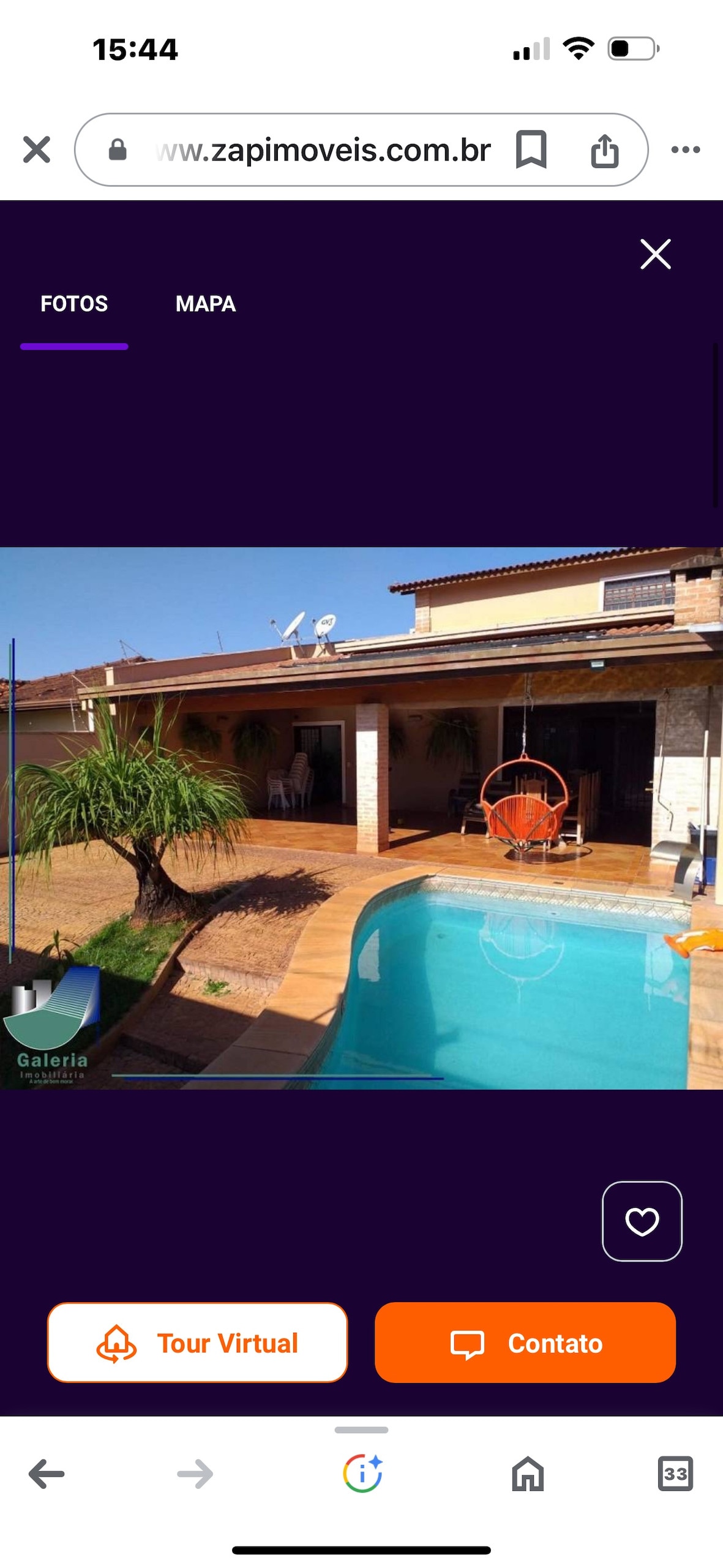 An inviting outdoor area features a calm swimming pool surrounded by wooden decking. A hanging chair is positioned nearby, with lush greenery adding to the open space. The area is shaded by an overhang, promoting a relaxed atmosphere for outdoor gatherings.