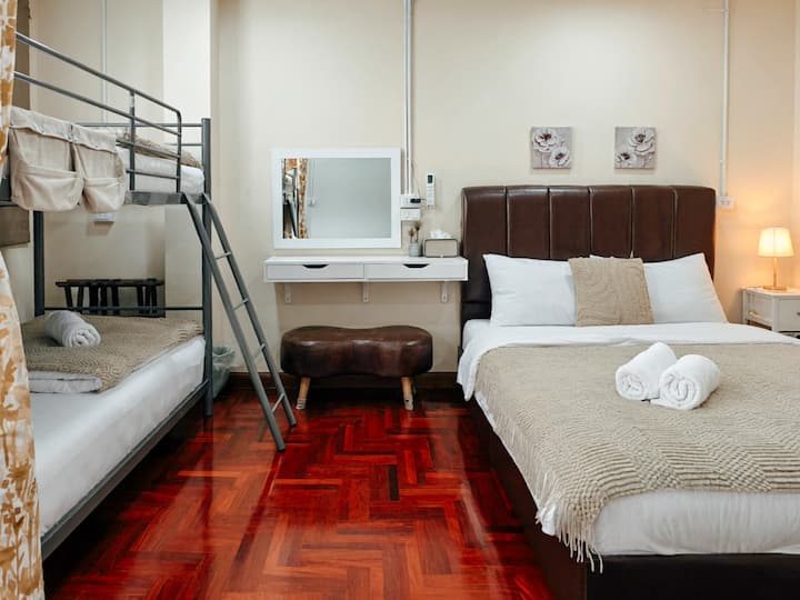 A cozy and functional room featuring a queen-size bed and bunk beds. Includes a makeup table.