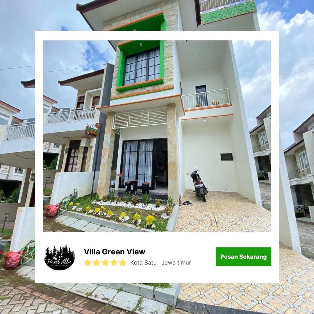 A modern villa exterior is shown, featuring a light-colored façade with green decorative accents. A manicured garden with small yellow flowers adorns the front, while a motorcycle is parked nearby. A covered porch is visible, providing access to the main entrance.