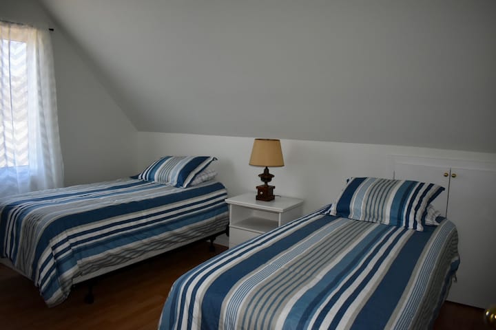 غرفة نوم في الطابق العلوي. سريران متماثلان وخزانة ملابس وخزانة كبيرة. 