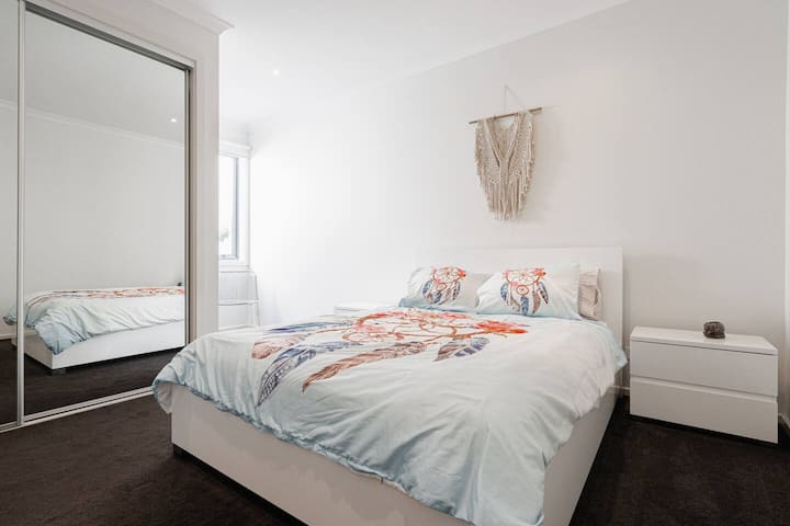 Sleep easy in the fourth bedroom. It highlights a queen-sized bed with large, mirrored wardrobes for storing your belongings.