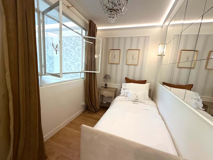 Chambre 2 avec lit simple et fenêtre astucieuse ouvrant sur le salon.