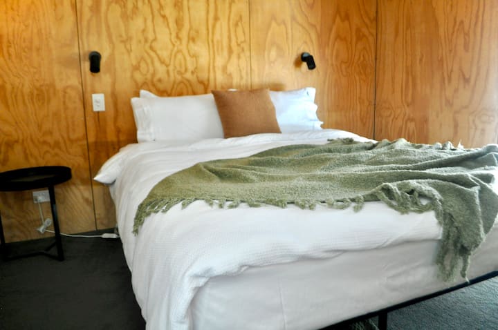 Toto je posteľ veľkosti Queen oblečená na leto. Užite si útulné postele a teplo drevených stien.