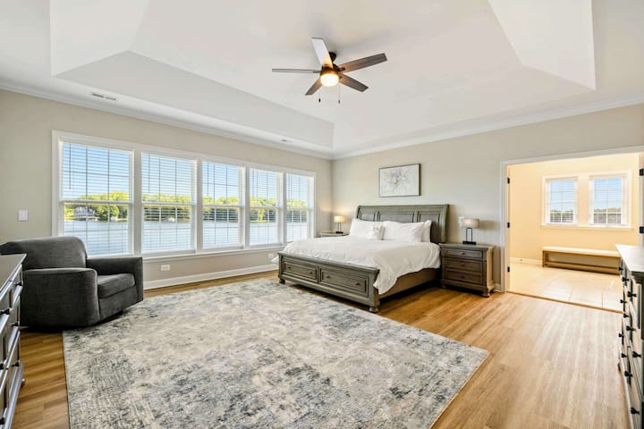 Spacious Primary Bedroom with a king-size bed, large windows, and an en-suite bathroom