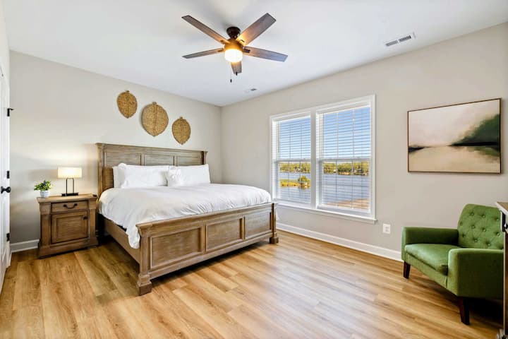 Spacious bedroom with a king-size bed, ceiling fan, and large windows offering lake views