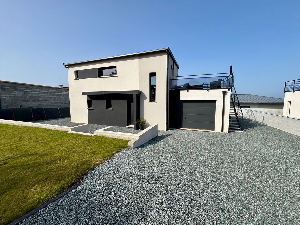 The exterior of the modern house features a clean, minimalist design with a two-story structure. A well-maintained lawn surrounds the property, while gravel paths lead to the entrance. A garage is visible on the side, and a staircase leads to the rooftop terrace, offering outdoor seating.