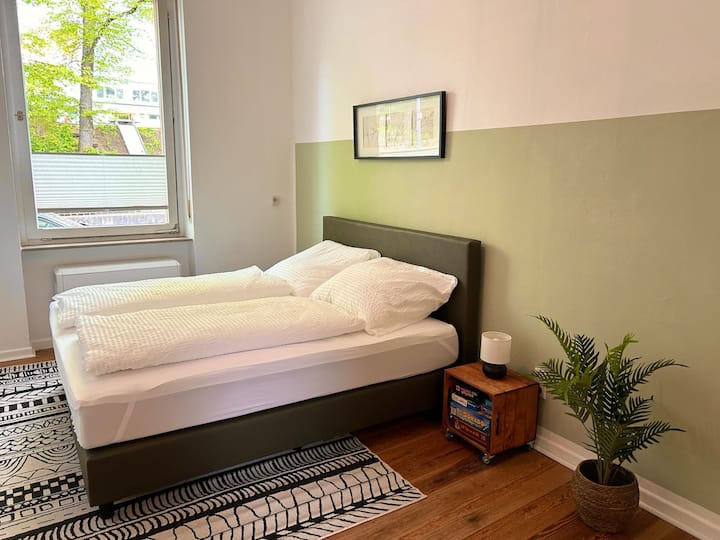 Im Schlafzimmer erwartet Sie ein hochwertiges Kingsize-Boxspringbett (180 x 200 cm) für Ihren erholsamen Schlaf. Ein offener Kleiderschrank bietet Stauraum für die Kleidung. Die Außenrollos ermöglichen eine vollständige Abdunkelung des Raumes.