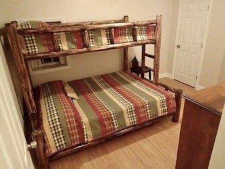 בחדר השינה הזה יש מיטת קומתיים עם מיטת קווין סייז למטה ותאום ארוך במיוחד למעלה.  