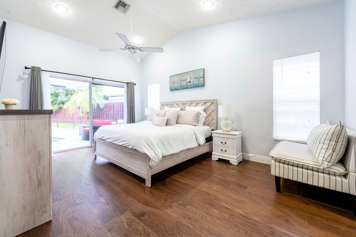 חדר שינה ראשי עם מיטת קינג סייז, טלוויזיה חכמה, חדר רחצה צמוד, ארונות וגישה לבריכה ולג'קוזי.