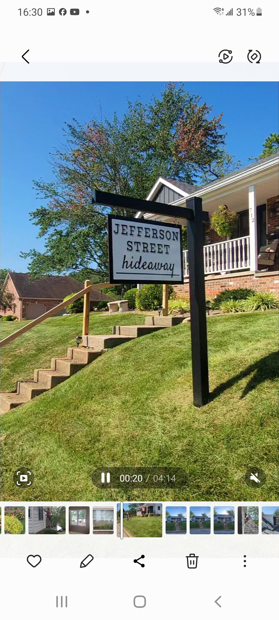 A black wooden sign with white text reading 'JEFFERSON STREET hideaway' is prominently displayed. The sign is situated near a set of grassy steps leading up to a welcoming porch adorned with greenery and brick accents, under a clear blue sky.