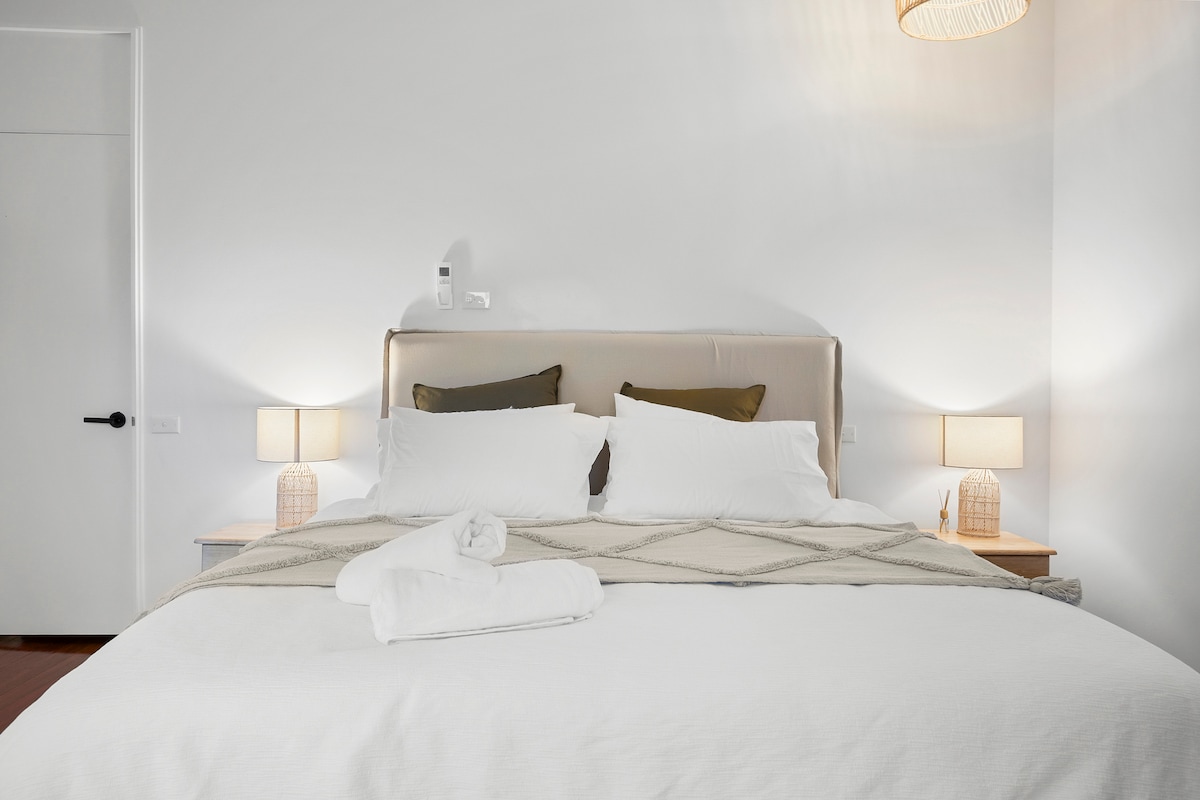 Kitanda kipya cha ukubwa wa kifalme kilicho na meza za kando ya kitanda na taa za kusoma.  