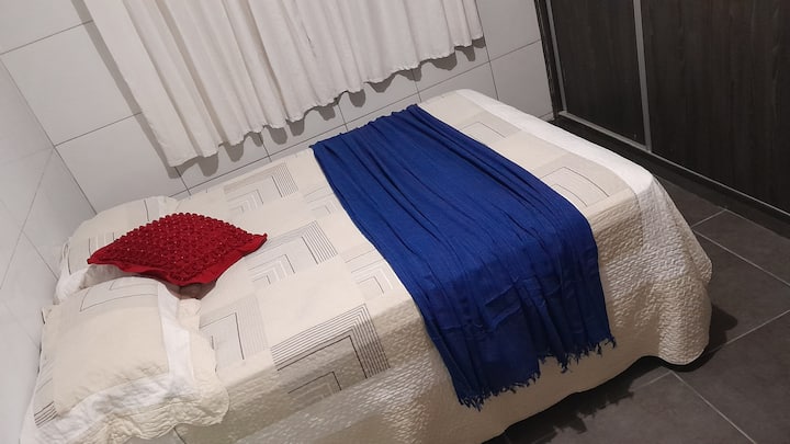 宽敞的卧室，配有双人床、衣柜、扶手椅、地毯、床上用品、空调和套房卫生间。