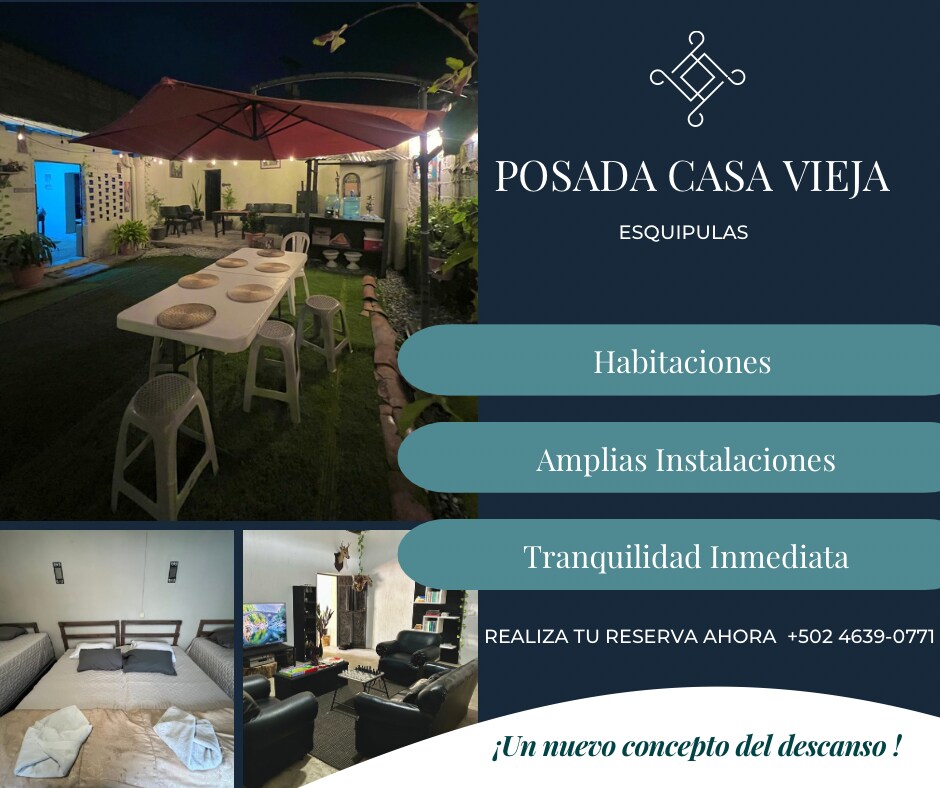 An outdoor dining area is featured, set with a large table and multiple chairs, covered by an umbrella. Lush greenery surrounds the space, enhancing an atmosphere for relaxation. The interior displays cozy seating and well-arranged bedding, suitable for group accommodations.