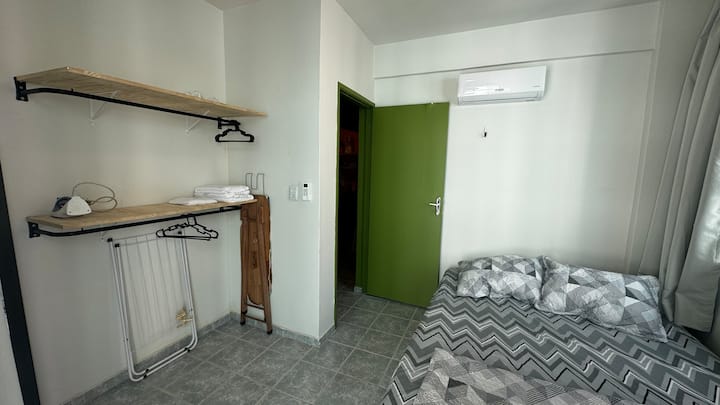 Chambre à coucher avec climatiseur à deux blocs, grand lit (queen size) avec drap et douillette, oreillers avec taies, cintres, étagères, bureau et chaise, miroir et d'autres commodités comme un fer à repasser, un séchoir à cheveux, etc.