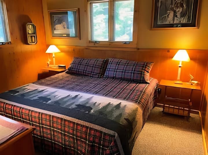 Hauptschlafzimmer 2: 
Dieses Hauptschlafzimmer auf der Hauptebene verfügt über ein gemütliches Kingsize-Bett und warme Hüttendetails. 
Ideal für Gäste, die sowohl Komfort als auch einfachen Zugang zu den Hauptwohnbereichen wünschen.