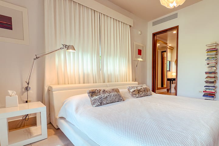 Elegante y acogedor: nuestra habitación muestra una cama bellamente decorada con una elegante lámpara de techo, creando un ambiente cálido y acogedor para una estadía tranquila.