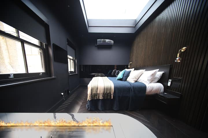 นอนหลับเหมือนราชวงศ์! เตียงซูเปอร์คิงไซส์ขนาด 180x200 ห้องน้ำ/ห้องนอนที่มีพื้นที่เปิดโล่งพร้อมตู้เสื้อผ้าแบบวอล์คอินช่องแสงขนาดใหญ่ทีวีและมู่ลี่ไฟฟ้าสีดำเพื่อการนอนหลับที่สะดวกสบายที่สุด เตาผิงเอทานอลแบบชีวภาพติดกับอ่างอาบน้ำเพื่อการพักผ่อนที่ดีที่สุด