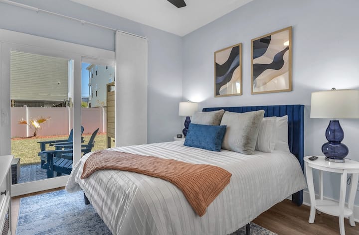 เตียงควีนไซส์ชั้น 1 พร้อมห้องน้ำในตัวสมาร์ททีวีตู้เสื้อผ้าและลานบ้านตกแต่งด้วยเก้าอี้ adirondack 4 ตัวที่มองเห็นสวนหลังบ้าน