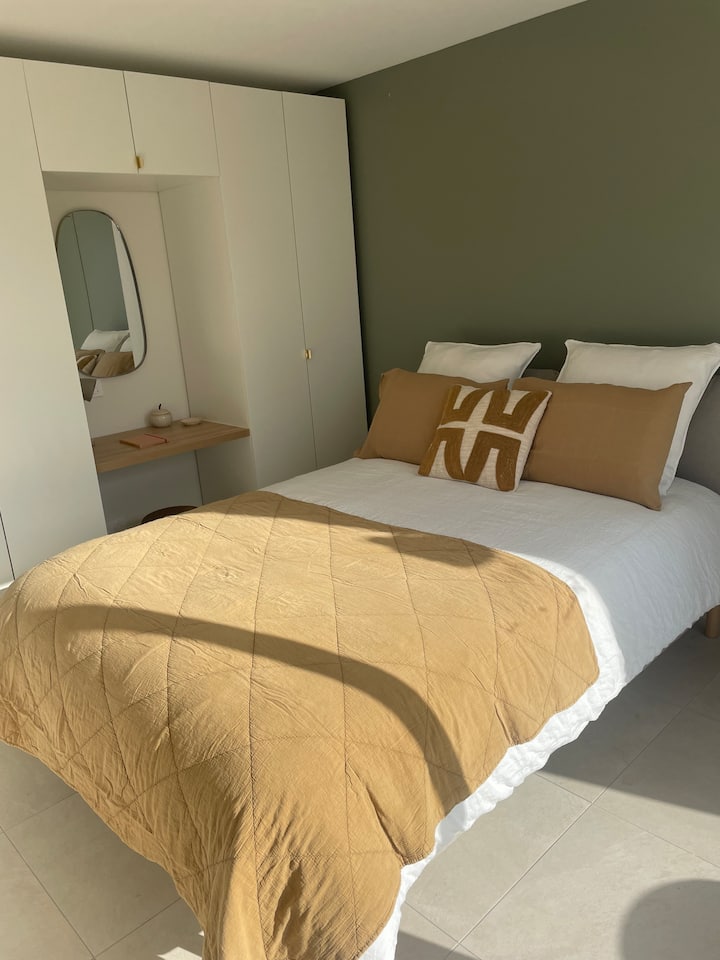 חדר שינה קטן עם מיטה 140. מפרץ הזזה שנפתח למרפסת שטופת שמש קטנה בבוקר. 