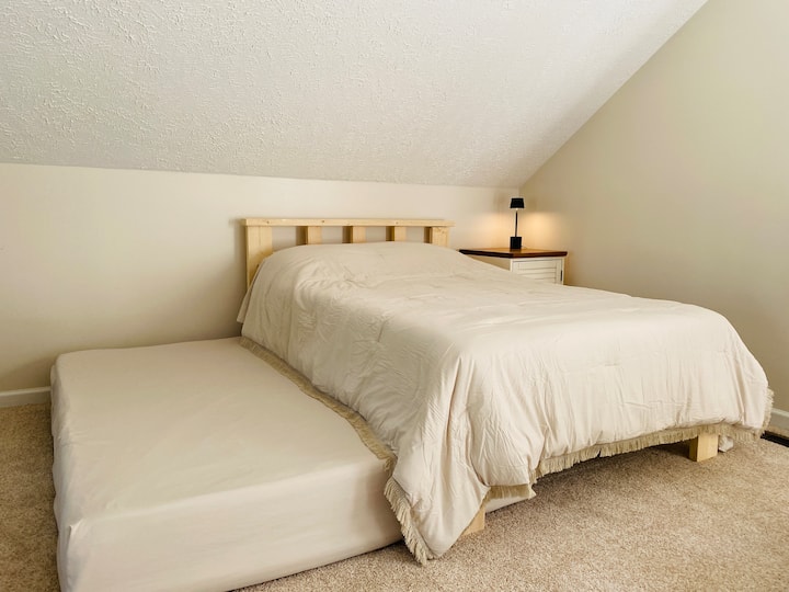 Deux lits doubles dans un loft, avec équipement d'exercice et espace de travail.