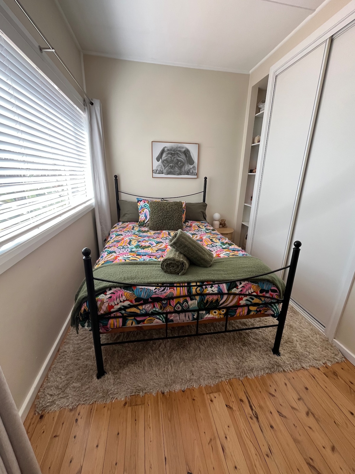 Ორადგილიანი საწოლი უამრავი დასაკიდი და უჯრით. Ოთახში ასევე არის ვენეციური ჟალუზები და შავი ფარდები. 